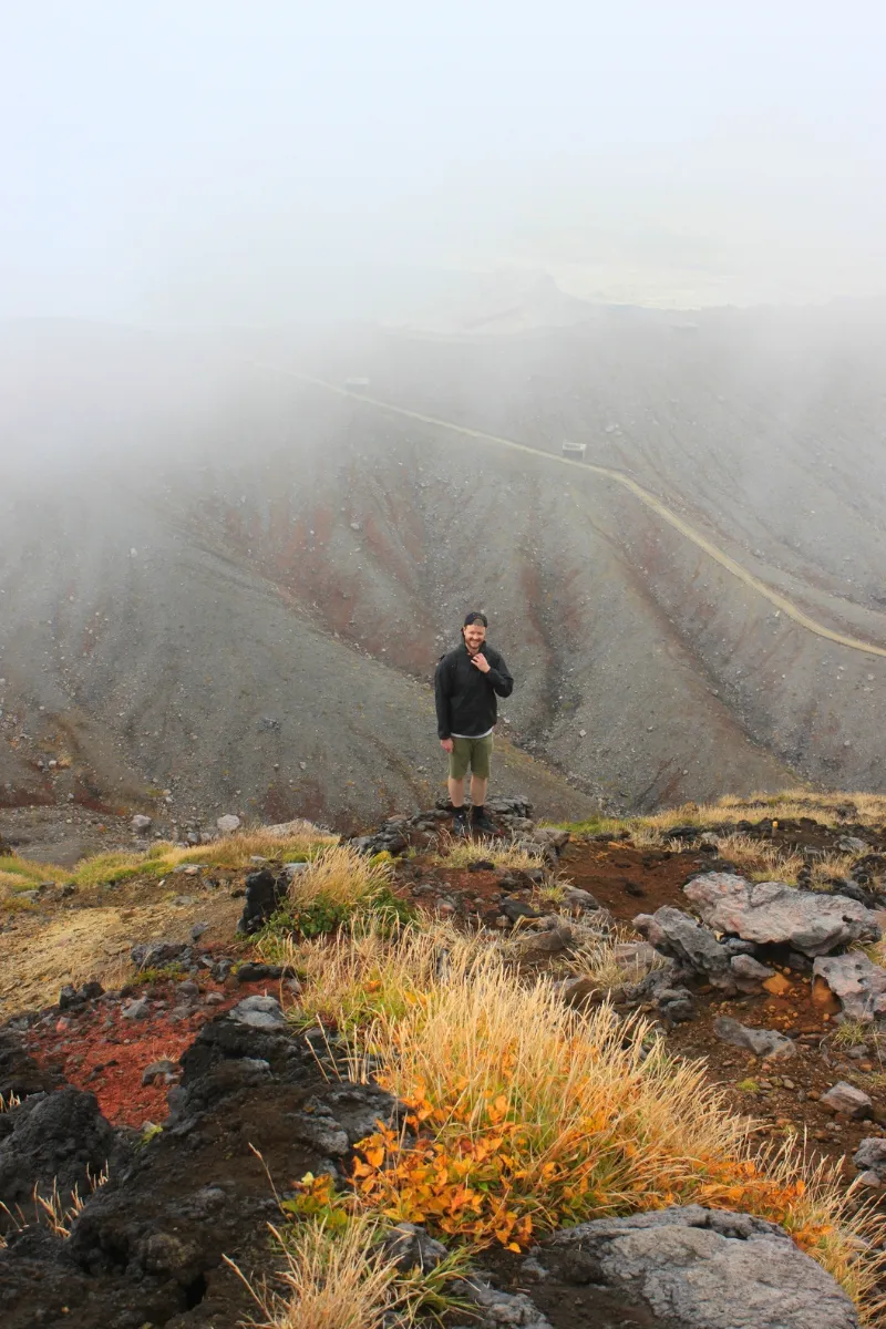 Mann steht im Nebel auf Nakadake, Mount Aso