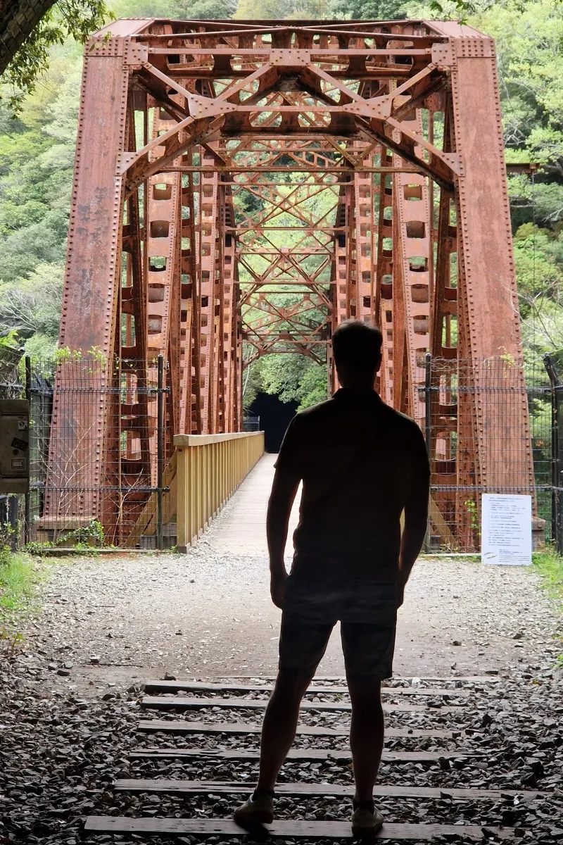 Mann steht vor rostiger Brücke