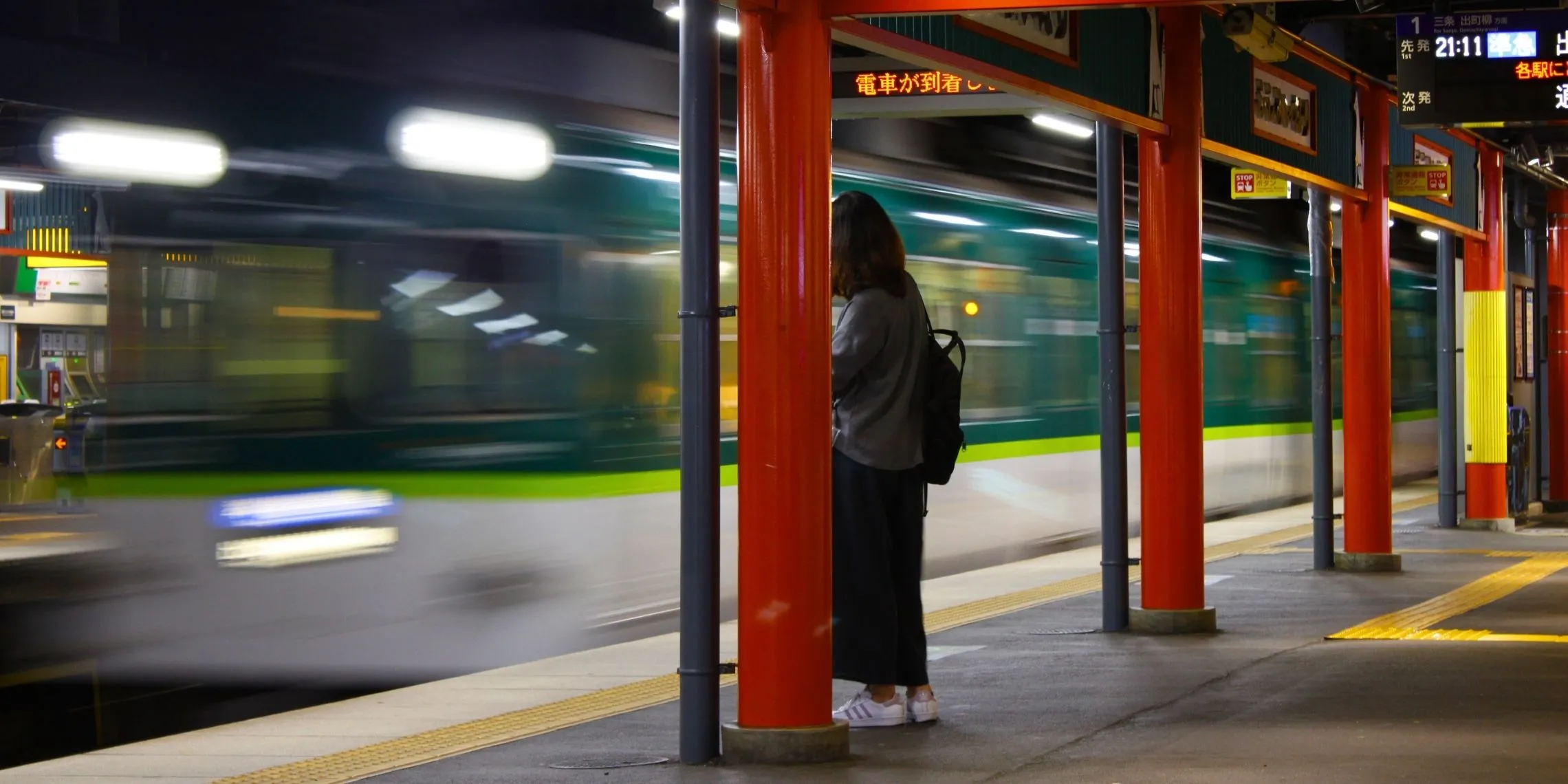 Eine junge Frau wartet abends an der Inari Station auf den Zug