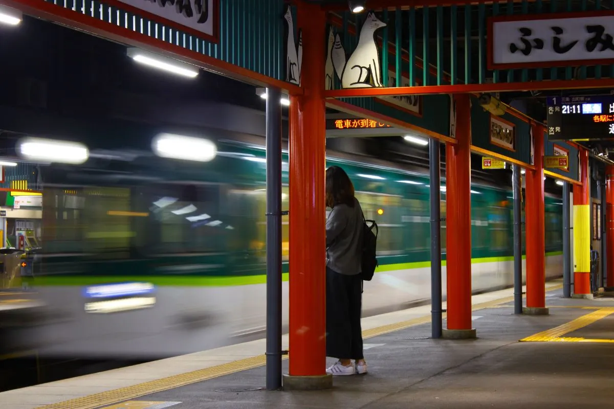Eine junge Frau wartet abends an der Inari Station auf den Zug