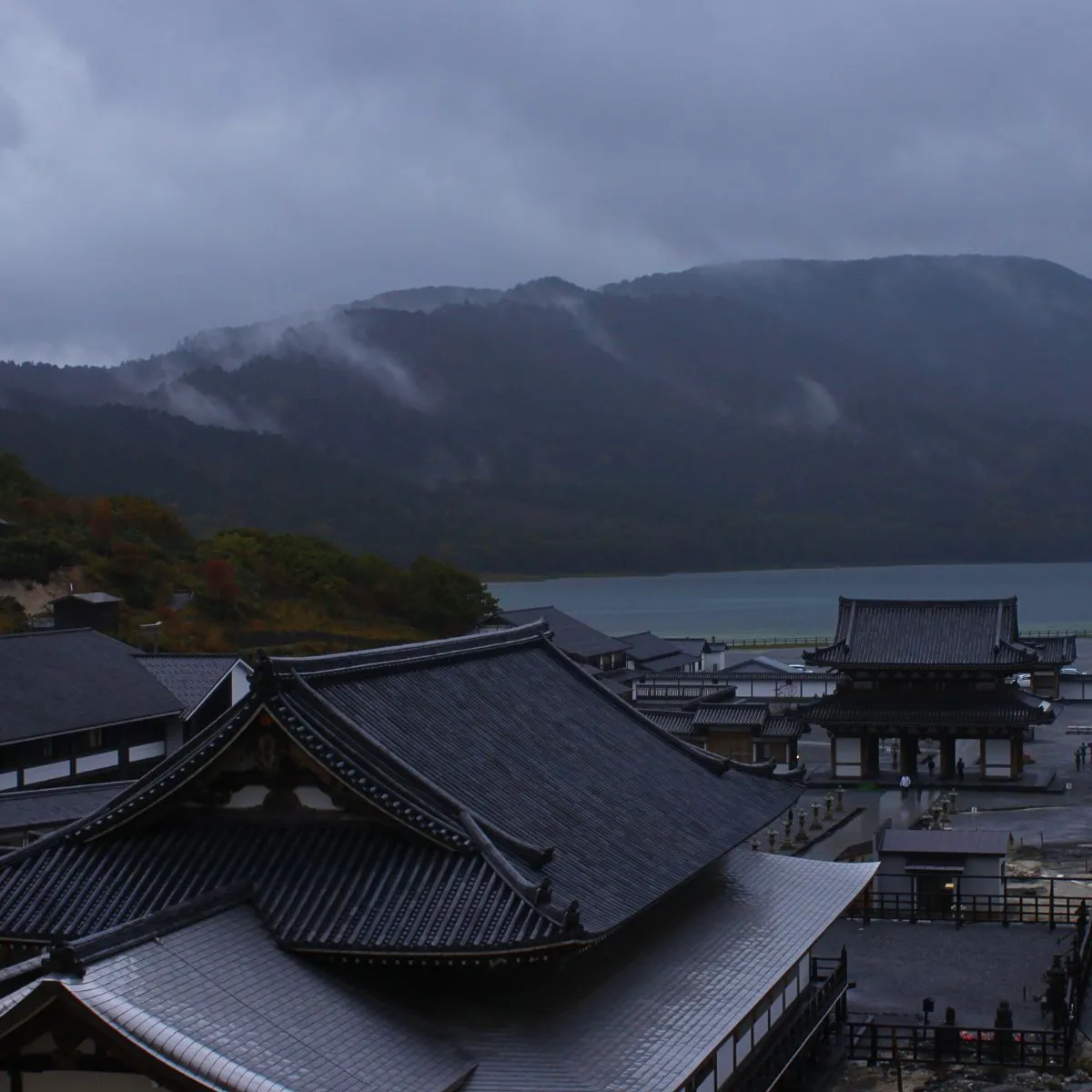 Dunkle Wolken über dem Bodaiji-Tempel auf dem Gipfel des Osorezan, im Hintergrund der Gipfelsee