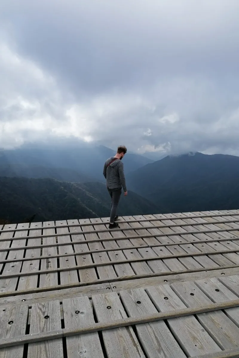 Mann steht am Rande einer Holzplattform auf dem Gipfel von Mount Tsurugi im Iya Valley