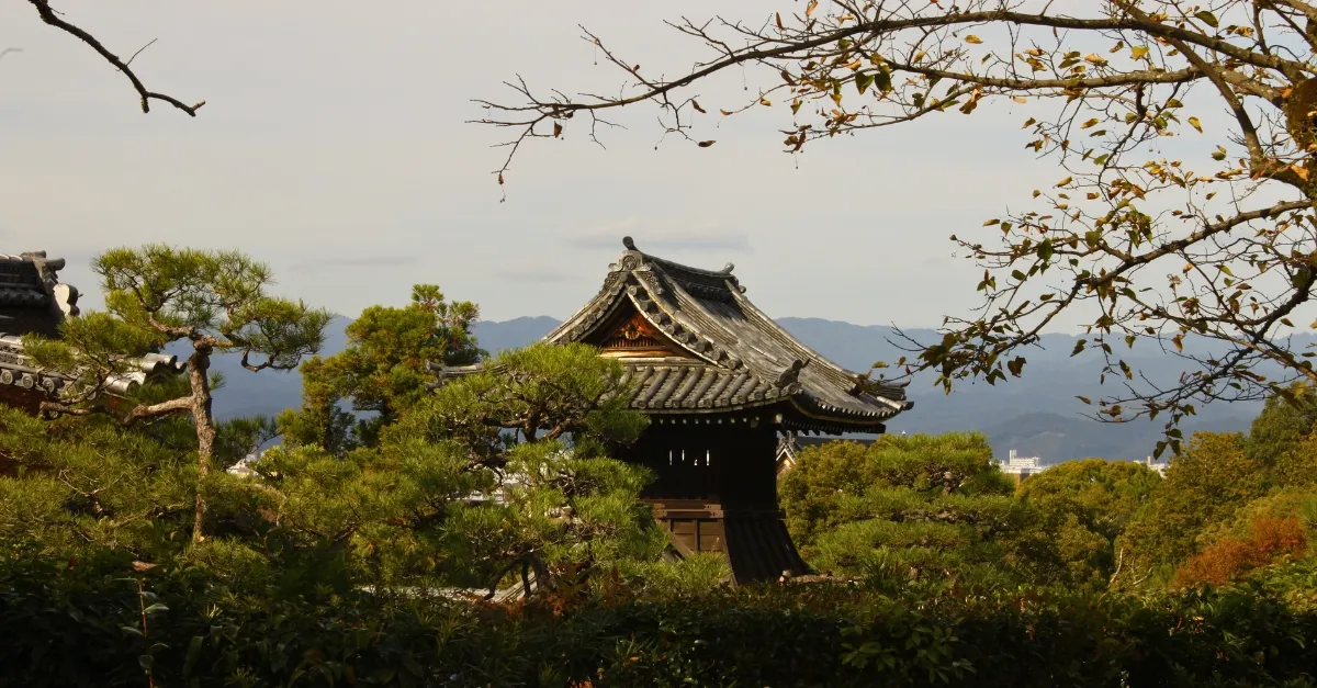 Blick auf einen Tempel in Kyoto, der teilweise hinter Bäumen verborgen ist