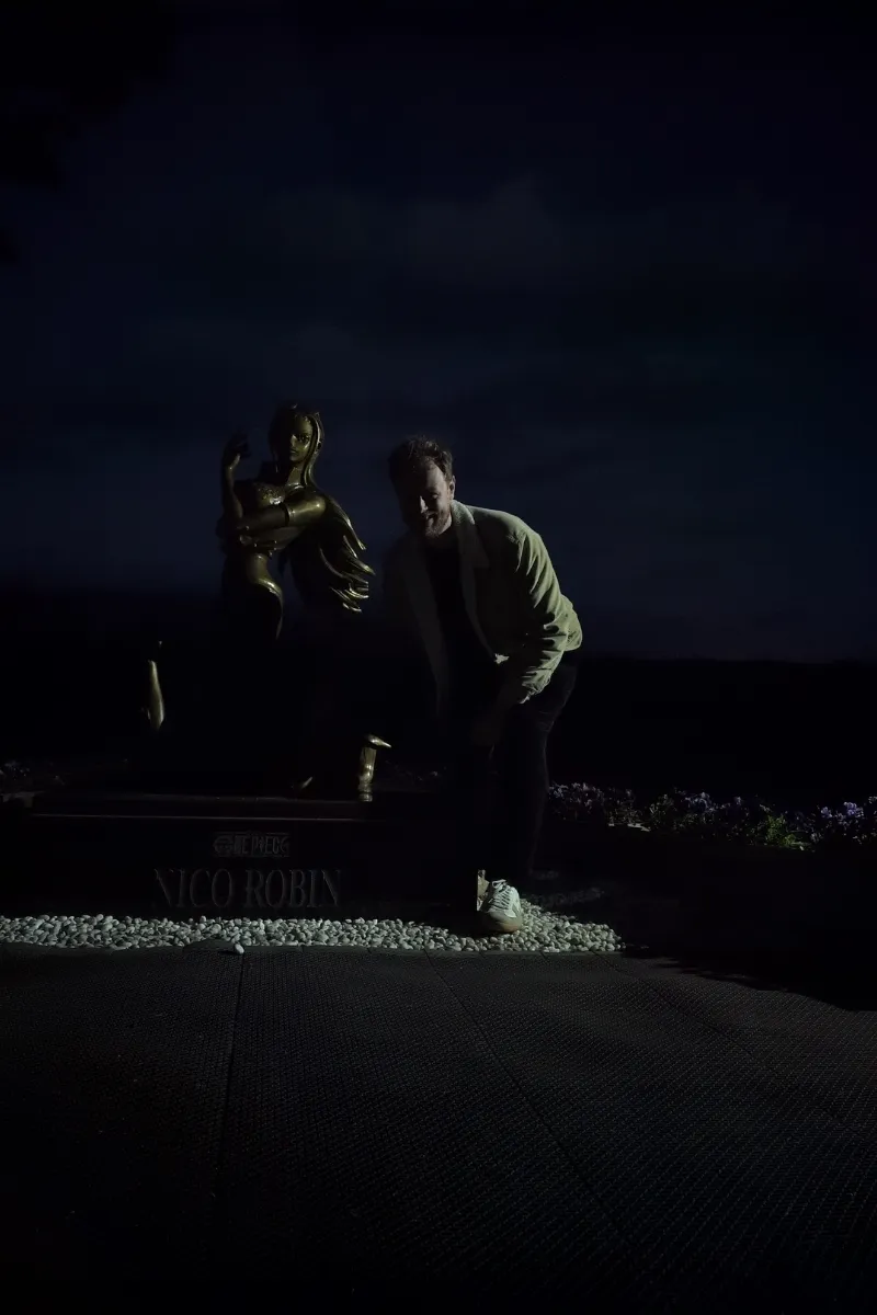 Mann kniet neben der Statue von Robin nahe Aso, im Dunklen