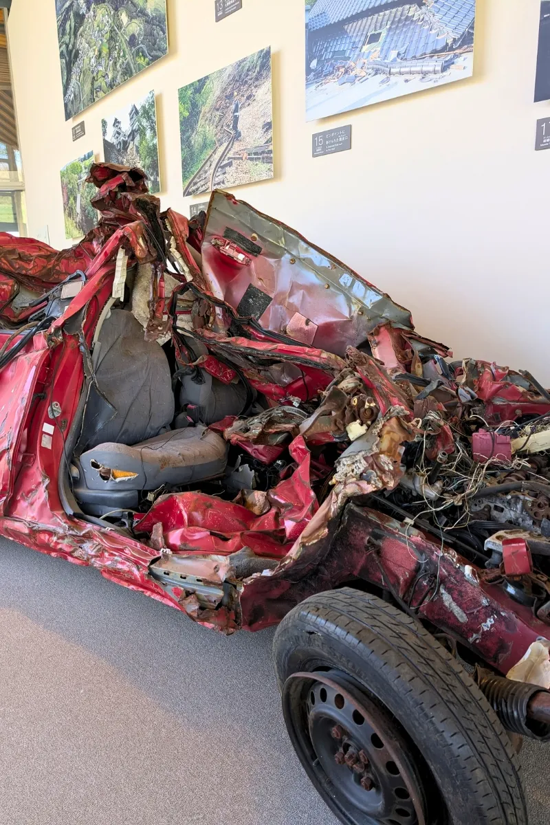 Exponat eines Autos im KIOKU-Kumamoto Earthquake Museum, welches durch das Kumamoto-Erdbeben 2016 zerstört wurde