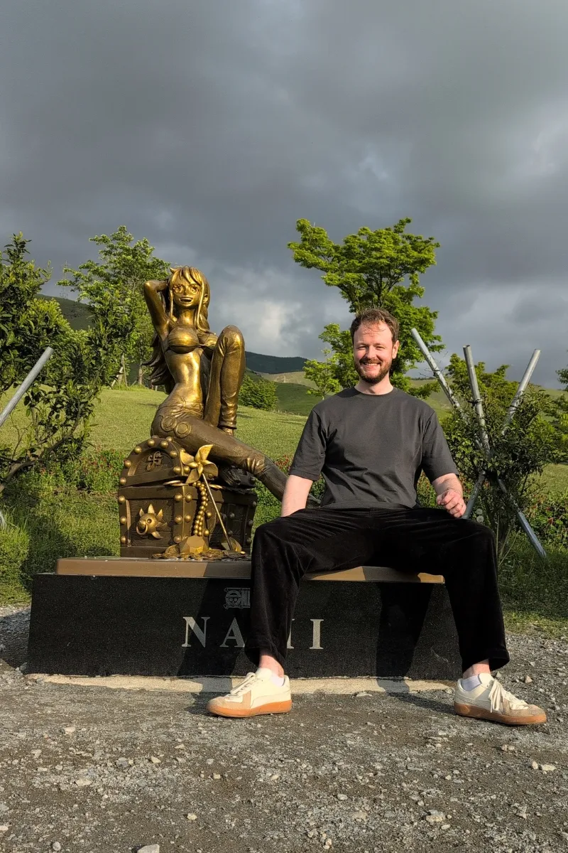 Mann sitzt neben der Nami-Statue in der Präfektur Kumamoto