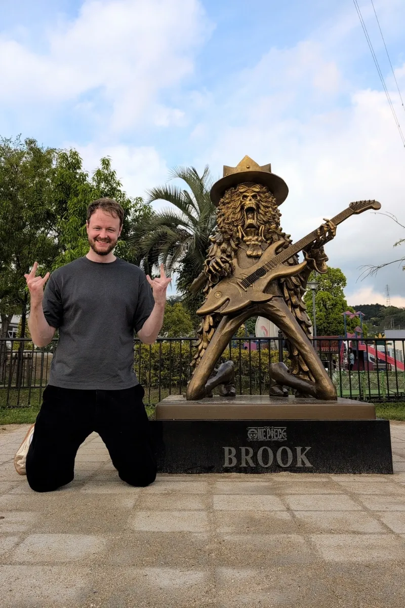 Mann posiert neben Statue des One Piece-Crewmitglieds Brook in Mifune Town, Kumamoto.