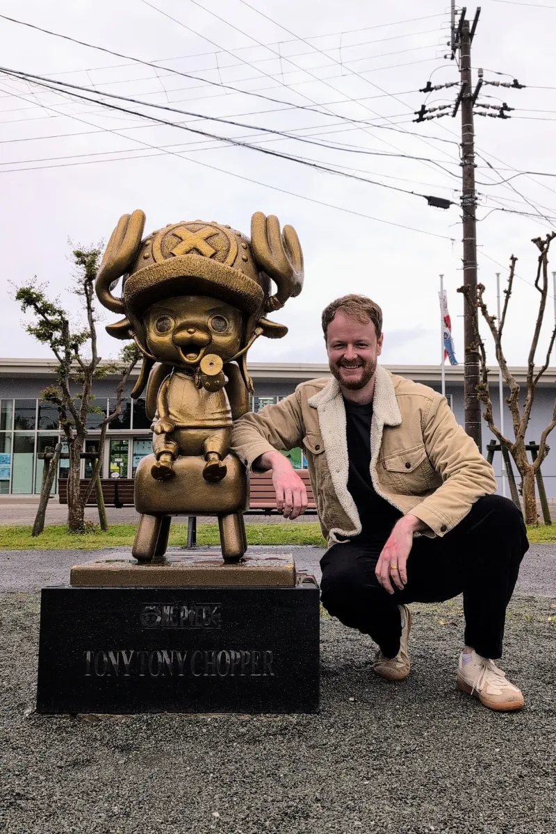 Mann lehnt sich an Chopper-Statue an auf dem Vorplatz des Kumamoto-Zoos