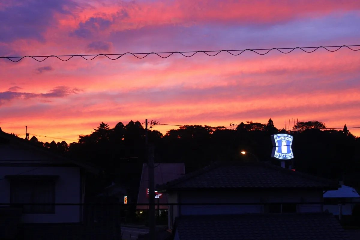 Das Werbeschild des Lawson Convenience Stores von Aso vor einem lächerlich schönen Sonnenuntergang