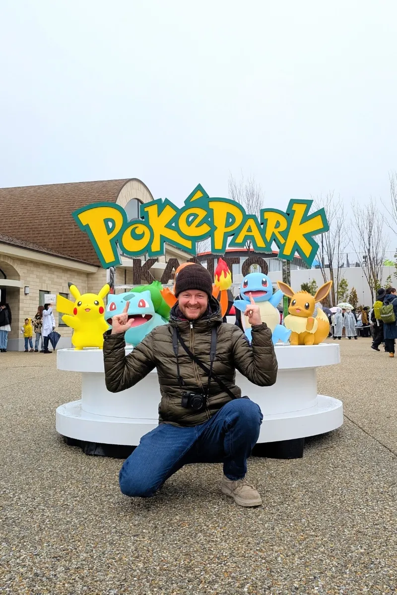 Gutaussehender Mann posiert vor dem Schild des Pokepark Kanto