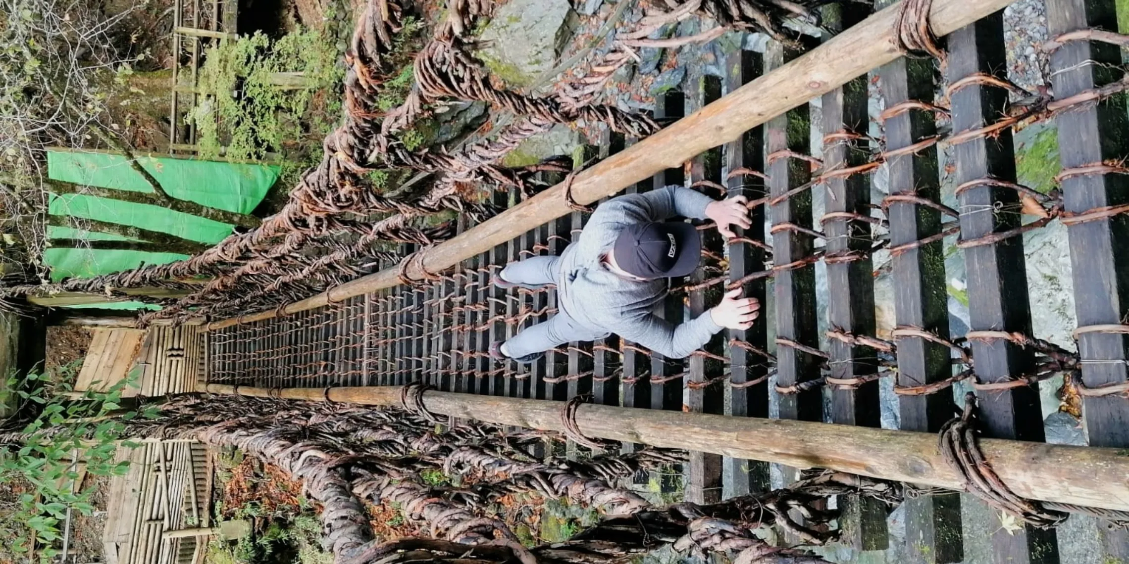Mann hängt in einer optischen Illusion an der Kazurabashi-Lianenbrücke