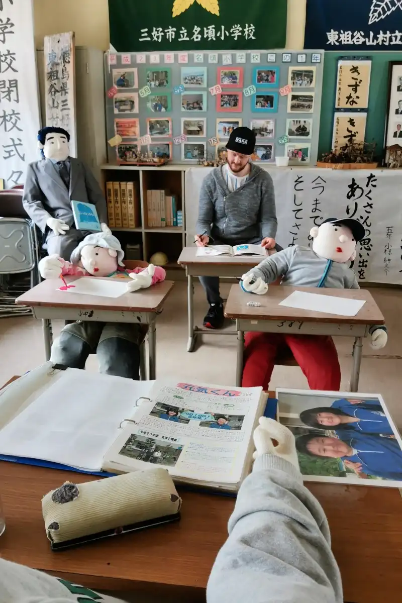 Mann lernt im Klassenzimmer von Vogelscheuchen umzingelt im Nagoro Village